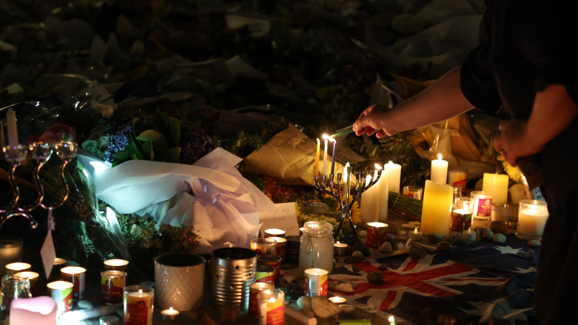 Опечален запалва свещ на импровизиран мемориал на плажа Бондай в Сидни, Нов Южен Уелс, Австралия, 16 декември 2025 г.